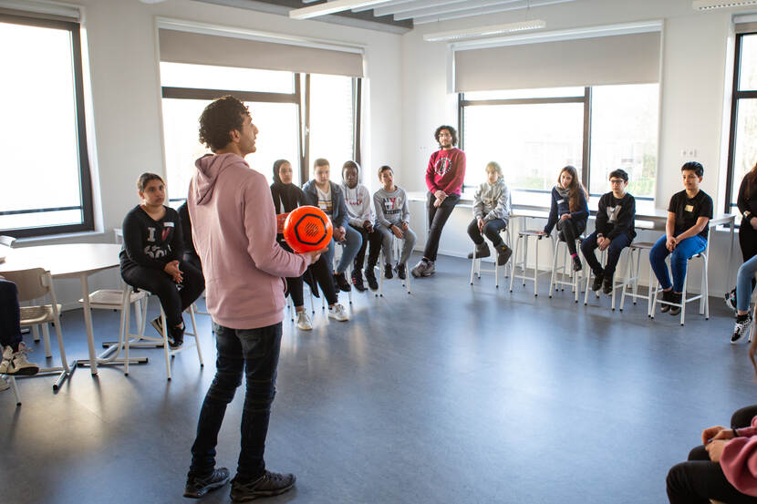 Soufiane Touzani staat voor de klas en legt leerlingen iets uit.